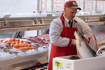 A Market Basket Seafood Manager inspecting the seafood delivery