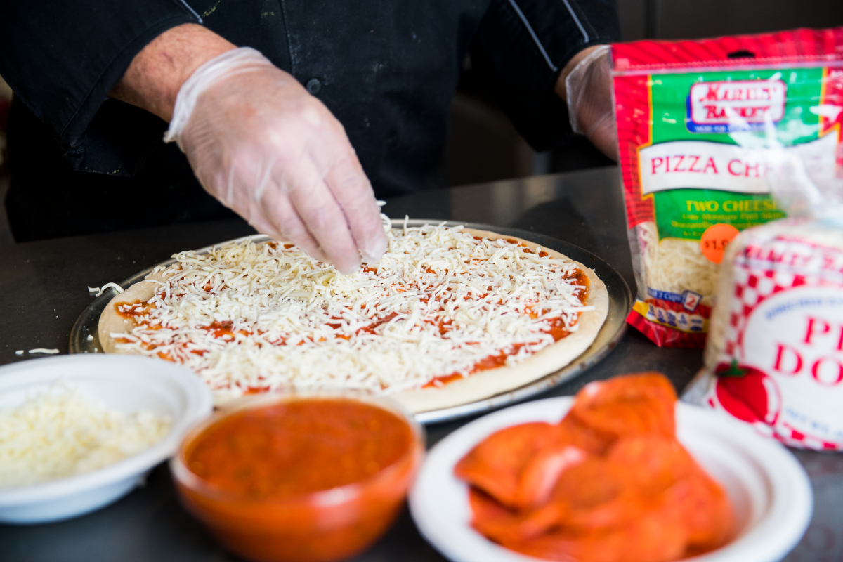 Market Basket make your own pizza, spreading the cheese