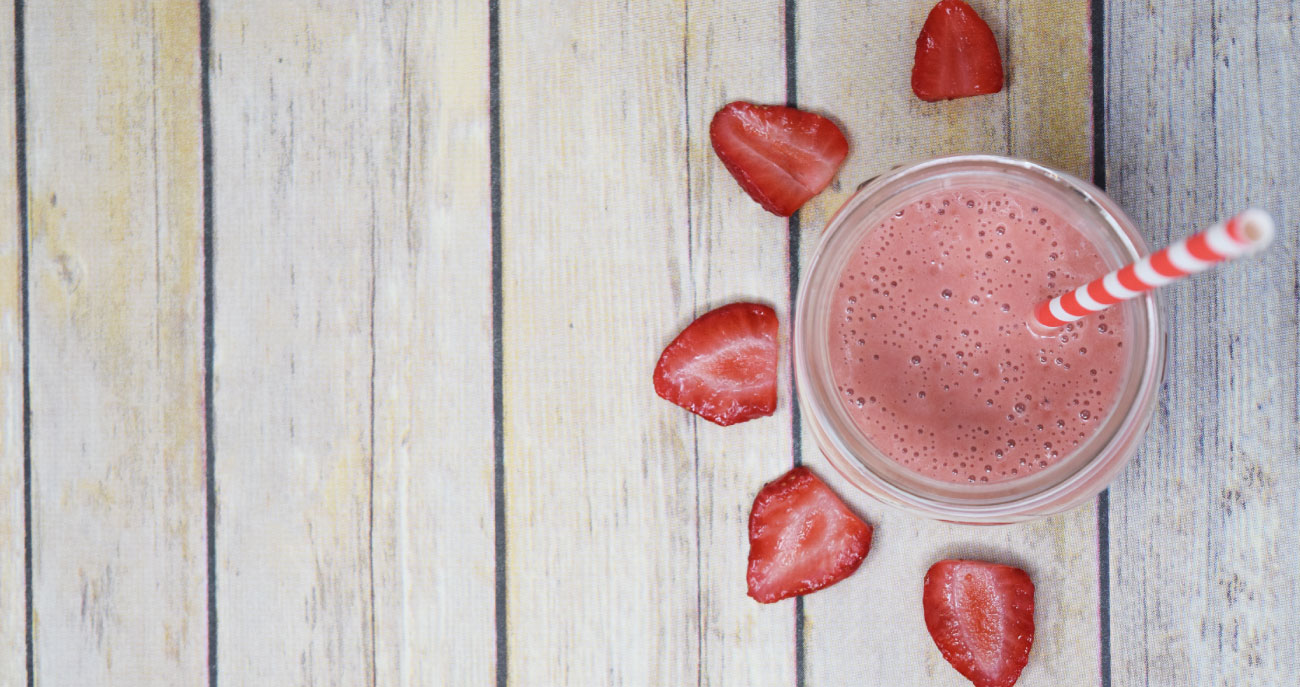 Strawberry Beet Smoothie with sliced strawberries laid out in a flower form around the mason jar that contains the smoothie